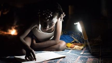 Une écolière apprend ses leçons, éclairée par une lampe solaire fabriquée au Burkina Faso par l'entreprise Lagazel en 2020 (Entreprise Lagazel)