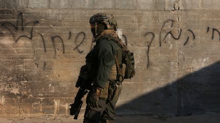 Un membre des forces de s&eacute;curit&eacute; isra&eacute;liennes devant la maison incendi&eacute;e &agrave; Doma (Cisjordanie), le 31 juillet 2015. Un b&eacute;b&eacute; palestinien y a &eacute;t&eacute; br&ucirc;l&eacute; vif. (JAAFAR ASHTIYEH / AFP)