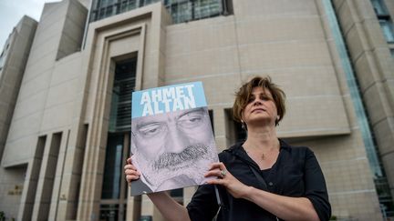 Une journaliste turque pose avec une photo d'Ahmet Altan devant le Palais de Justice d'Istanbul, le 18 juin 2017. (OZAN KOSE / AFP)