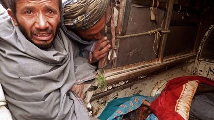 Deux Afghans pleurent les civils tu&eacute;s le 11 mars 2012 par un soldat am&eacute;ricain dans la province de Kandahar. (JANGIR / AFP)