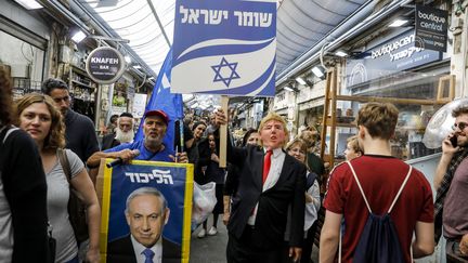 Des soutiens de&nbsp;Benjamin Netanyahu avec un masque de Donald Trump dans un marché, le 7 avril.&nbsp; (MENAHEM KAHANA / AFP)