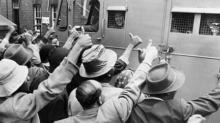 Des sympathisants de l'ANC saluent le passage d'un fourgon cellulaire transportant des militants anti-apartheid, le 28 décembre 1956. (AFP)