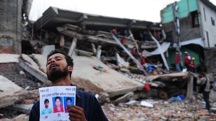 Le 28 avril 2013, un homme brandit la photo de ses proches devant l'immeuble abritant des ateliers textiles qui s'est effrondr&eacute; pr&egrave;s de Dacca au Bangladesh. (MUNIR UZ ZAMAN / AFP)