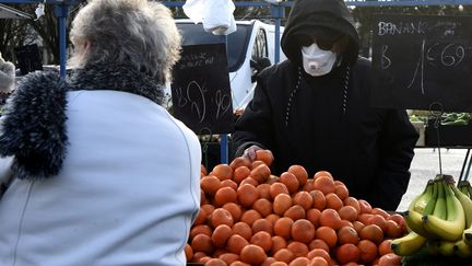 Un marchand de fruits et légumes porte un masque sur le marché de Crépy-en-Valois (Oise), le 1er mars 2020. (FRANCOIS LO PRESTI / AFP)