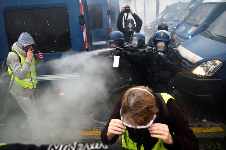 Des policiers aspergent de gaz lacrymogène des manifestants, le 1er décembre 2018, à Paris. (LUCAS BARIOULET / AFP)