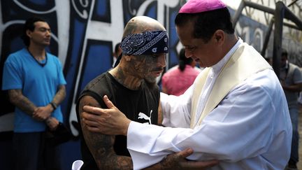 Un pr&ecirc;tre (D) parle avec un membre du gang Mara Salvatrucha dans la prison de Ciudad Barrios (Salvador), le 19 juin 2012. (JOSE CABEZAS / AFP)