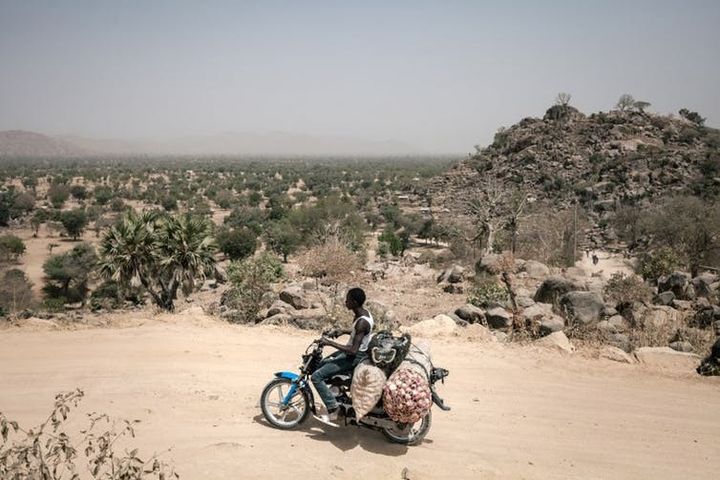 Un homme transporte des oignons dans la région montagneuse de Koza, février 2018, au nord-est du Cameroun où sévissent les hommes de Shekau. Cerains chauffeurs de motos-taxis (achabas) ont été des partisans importants de Boko Haram au début des années 2000 . (Alexis Huguet/AFP)