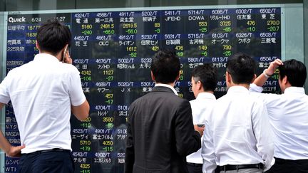 Des passants regardent les cours chahutés de la Bourse de Tokyo, alors que le Brexit semble l'emporter au Royaume-Uni, le 24 juin 2016. (KAZUHIRO NOGI / AFP)