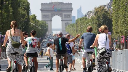 Des touristes à vélo sur 'avenue des Champs-Élysées, à Paris, le 30 juillet 2024. (JEAN-MARC LOOS / MAXPPP)