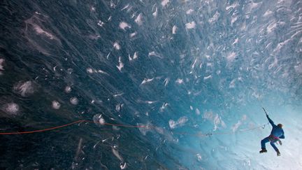 Un homme tente d'escalader un mur de glace dans une grotte &agrave; 40 m&egrave;tres de profondeur sous la mer de Glace &agrave; Chamonix (Haute-Savoie), le 30 octobre 2013. (JONATHAN GRIFFITH / SOLENT NEWS / SIPA)