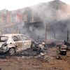 La carcasse d'un v&eacute;hicule devant des commerces incendi&eacute;s, apr&egrave;s une explosion au march&eacute; de Jos (Nigeria), le 20 mai 2014. (AFP)