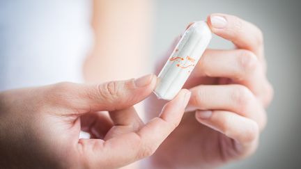 Une femme tient un tampon hygiénique, à Paris, en 2017. (GARO / PHANIE / AFP)