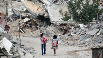 Des petites filles marchent devant des bâtiments détruits à Khan Yunis, dans le sud de la bande de Gaza, le 17 octobre 2024. (BASHAR TALEB / AFP)