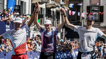 Kilian Jornet (au centre), vainqueur de l'UTMB 2022, entouré du deuxième Mathieu Blanchard (à g.) et du troisième Thomas Evans, le 27 août 2022. (JEFF PACHOUD / AFP)