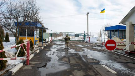 Un garde ukrainien se tient à un check-point à la frontière avec la Russie, le 16 février 2022. (SERGEY BOBOK / AFP)