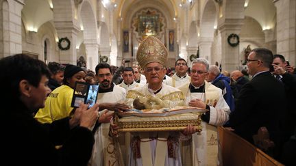 Le patriarche de J&eacute;rusalem porte une statuette de J&eacute;sus pendant la messe de No&euml;l &agrave; Bethl&eacute;em (Territoires palestiniens). (AMMAR AWAD / REUTERS)