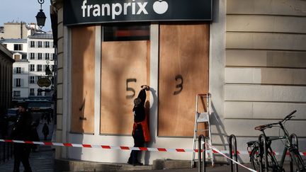 Un employé d'un supermarché&nbsp;installe des panneaux en bois sur sa devanture, le 17 décembre 2019, à Paris.&nbsp; (FRANCOIS GUILLOT / AFP)