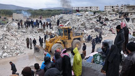 Des habitants et des sauveteurs&nbsp;à la recherche des victimes et des survivants parmi les décombres suite à un tremblement de terre dans le village de Besnaya, dans la province d'Idlib, au nord-ouest de la Syrie, à la frontière avec la Turquie, le 6 février 2023. (OMAR HAJ KADOUR / AFP)