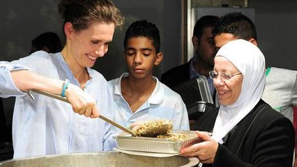 Asma al-Assad, épouse du président syrien et bénéficiaire de l'aide financière indirecte de l'ONU, servant la nourriture à des familles de déplacés, lors d'un iftar, dîner de rupture du jeûne du ramadan, le 4 août 2013. (HO/Facebook/AFP)