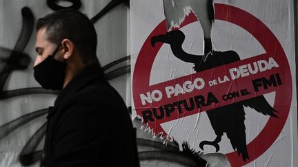 Un homme passe devant une pancarte contre le paiement de la dette auprès du FMI, à Buenos Aires (Argentine), le 22 mai 2020. (JUAN MABROMATA / AFP)