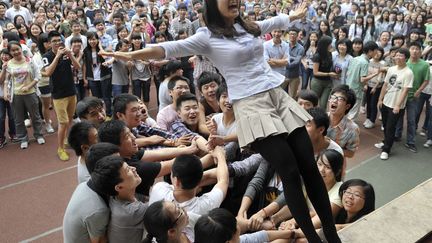 Un professeur se laisse tomber dans les bras de ses &eacute;l&egrave;ves lors d'un s&eacute;minaire anti-stress dans un lyc&eacute;e de Chongqing (Chine), le 28 mai 2012. (SHI TOU / REUTERS)