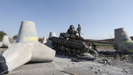 Des soldats ukrainiens inspectent un tank endommag&eacute;, le 6 septembre 2014, &agrave; un check-point &agrave;&nbsp;Marioupol (Ukraine). ( VASILY FEDOSENKO / REUTERS)