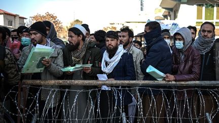 Des hommes attendent au bureau des passeports à Kaboul, le 18 décembre 2021. (MOHD RASFAN / AFP)