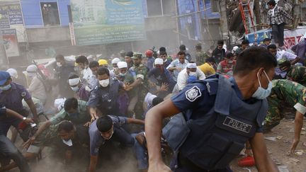 Des secouristes se pr&eacute;cipitent &agrave; l'&eacute;cart du Rana Plaza, apr&egrave;s que quelqu'un a averti (&agrave; tort) de l'effondrement d'un b&acirc;timent voisin, le 26 avril. (ANDREW BIRAJ / REUTERS)