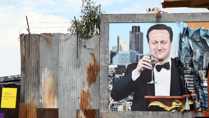 Une fresque des artistes&nbsp;Banksy et Block9&nbsp;repr&eacute;sente le Premier ministre britannique David Cameron avec une coupe de champagne, devant le quartier d'affaires londonien de Canary Wharf.&nbsp;Le tout, au milieu des t&ocirc;les rouill&eacute;es. (NATASHA QUARMBY / REX SHU / SIPA)