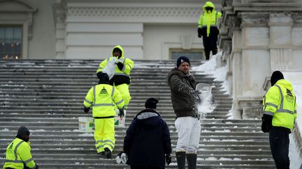 Des employés muncipaux jettent du sel sur les marches gelées du Capitole, à Washington. (CHIP SOMODEVILLA / GETTY IMAGES NORTH AMERICA / AFP)