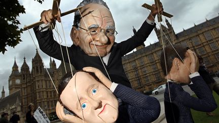 Un manifestant d&eacute;guis&eacute; en Rupert Murdoch manipule une marionnette du Premier ministre britannique, David Cameron. (ADRIAN DENNIS / AFP)