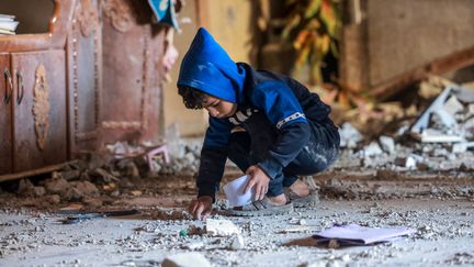 Un petite garçon palestinien ramasse des débris après un bombardement israélien à Rafah, dans le sud de la bande de Gaza, le 22 décembre 2023. (MOHAMMED ABED / AFP)