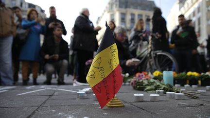 Un drapeau belge marqué de "Nous sommes tous Bruxelles" est déposé sur le mémorial improvisé, place de la Bourse à Bruxelles, après les attentats qui ont frappé la capitale belge mardi 22 mars 2016. (KENZO TRIBOUILLARD / AFP)