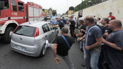 Des hommes s'en prennent au v&eacute;hicule de police qui transporte le meurtrier pr&eacute;sum&eacute; de quatre personnes vers le commissariat, vendredi 15 mai 2015, &agrave; Naples (Italie). (LAPORTA / AFP)