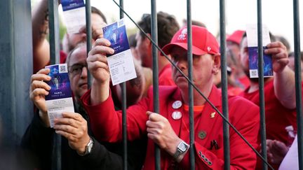 Des supporters de Liverpool coincés à l'extérieur du Stade de France montrent leur billet pour la finale de Ligue des champions, le 28 mai 2022. (ADAM DAVY / MAXPPP)