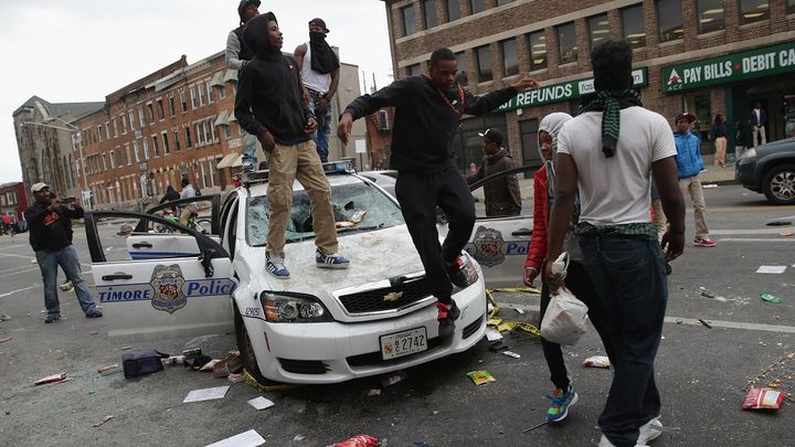 Des manifestants montent sur une voiture vandalis&eacute;e de la police de Baltimore, le 27 avril 2015. (CHIP SOMODEVILLA / GETTY IMAGES NORTH AMERICA / AFP)