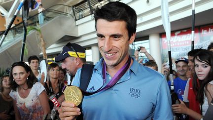 Tony Estanguet, le 14 ao&ucirc;t 2012, avec sa m&eacute;daille d'or d&eacute;croch&eacute;e aux JO de Londres, &agrave; son arriv&eacute;e &agrave; l'a&eacute;roport de Pau (Pyr&eacute;n&eacute;es-Atlantiques).&nbsp; (LAISSAC LUKE / AFP)