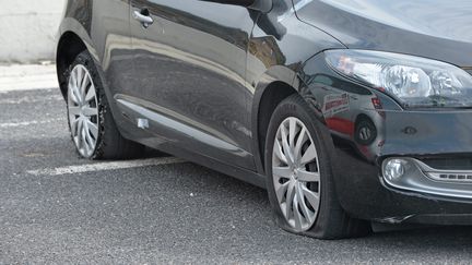 Une voiture avec les deux pneus crevés, le 25 mars 2016. (MAXPPP)