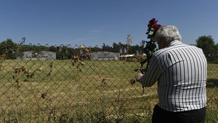 Un homme dépose une fleur en hommage aux Roms morts à Lety, en République tchèque. les bâtiments visibles sont ceux d'une élevage de porcs, construit sur le site du camp de concentration. (MICHAL CIZEK / AFP)