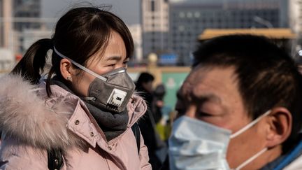 Une femme portant un masque de protection passe à côté d’un officier de police paramilitaire devant la gare de Pékin en Chine, le 21 janvier 2020 (photo d’illustration). (NICOLAS ASFOURI / AFP)