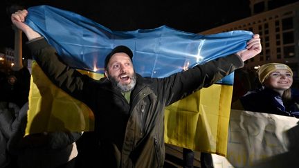 Un homme brandit un drapeau ukrainien pour célébrer la libération de Kherson (Ukraine), le 11 novembre 2022 à Kiev. (GENYA SAVILOV / AFP)