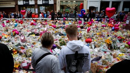 Des passants se recueillent, le 29 mai 2017 à Manchester (Royaume-Uni), devant le mémorial improvisé aux victimes de l'attentat. (PHIL NOBLE / REUTERS)