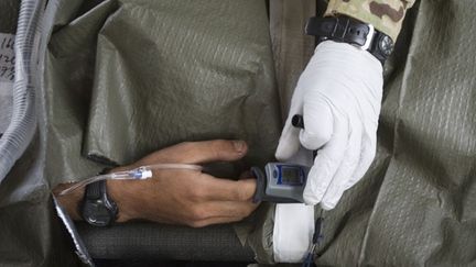 Le sergent vérifie aussi que sa sonde à oxygène est bien installée. Le blessé sera déposé très rapidement à la base. (AFP PHOTO/BEHROUZ MEHRI)