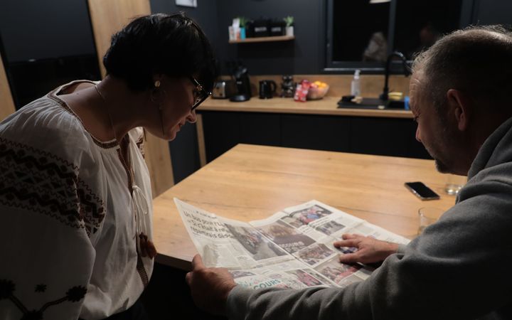 Olena et Jean-François feuillettent le numéro du quotidien "L'Indépendant", qui raconte leur voyage en bus en avril 2022, à Cazilhac (Aude), le 19 décembre 2024. (ZOE AUCAIGNE / FRANCEINFO)