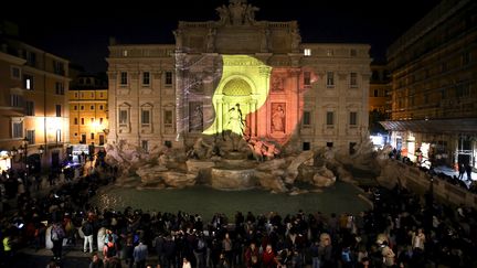 Des centaines de personnes se sont rassemblée devant la fontaine de Trevi à Rome (Italie), sur laquelle était projeté&nbsp;le drapeau belge. (STEFANO RELLANDINI / REUTERS)