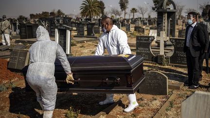 Des salariés des pompes funèbres déplacent un cercueil contenant une victime du Covid-19 au cimetière d'Avalon à Soweto (Afrique du Sud), le 24 juillet 2020.&nbsp; (MICHELE SPATARI / AFP)