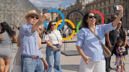 Des touristes devant la pyramide du Louvre, à Paris, pendant les Jeux olympiques, le 7 août 2024. (CLAIRE SERIE / HANS LUCAS / AFP)