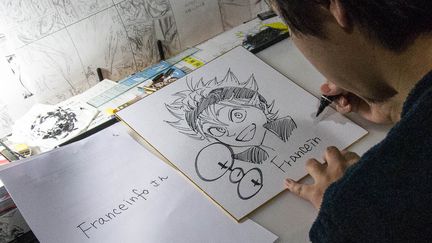 Yûki Tabata, l'auteur deu manga "Black Clover" dédicace un dessin à franceinfo à Tokyo (Japon), le 6 avril 2018. (ELODIE DROUARD / FRANCEINFO)