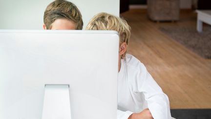 Deux enfants derrière un écran d'ordinateur, le 11 décembre 2012. (WWW.MIEN.BE / IMAGE SOURCE / AFP)