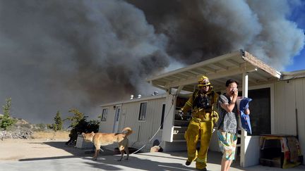 Un pompier aide une famille à évacuer sa maison dans le comté de San Bernardino, le 16 août 2016. (WILL LESTER/AP/SIPA / AP)